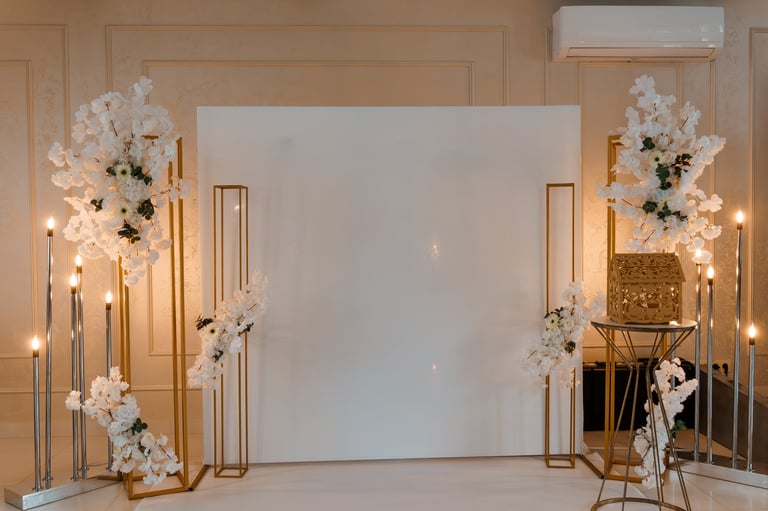 Luxurious wedding stage decoration with white flowers, gold metal frames, candles and blank canvas backdrop