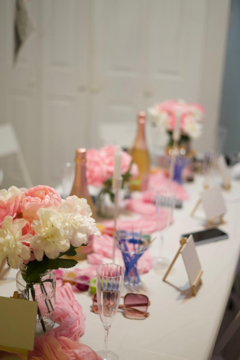 Elegant table setting with pink and white peonies, champagne bottles, and place cards for a formal celebration event